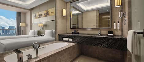A modern hotel bathroom with a large bathtub, a separate shower area, and a large mirror.
