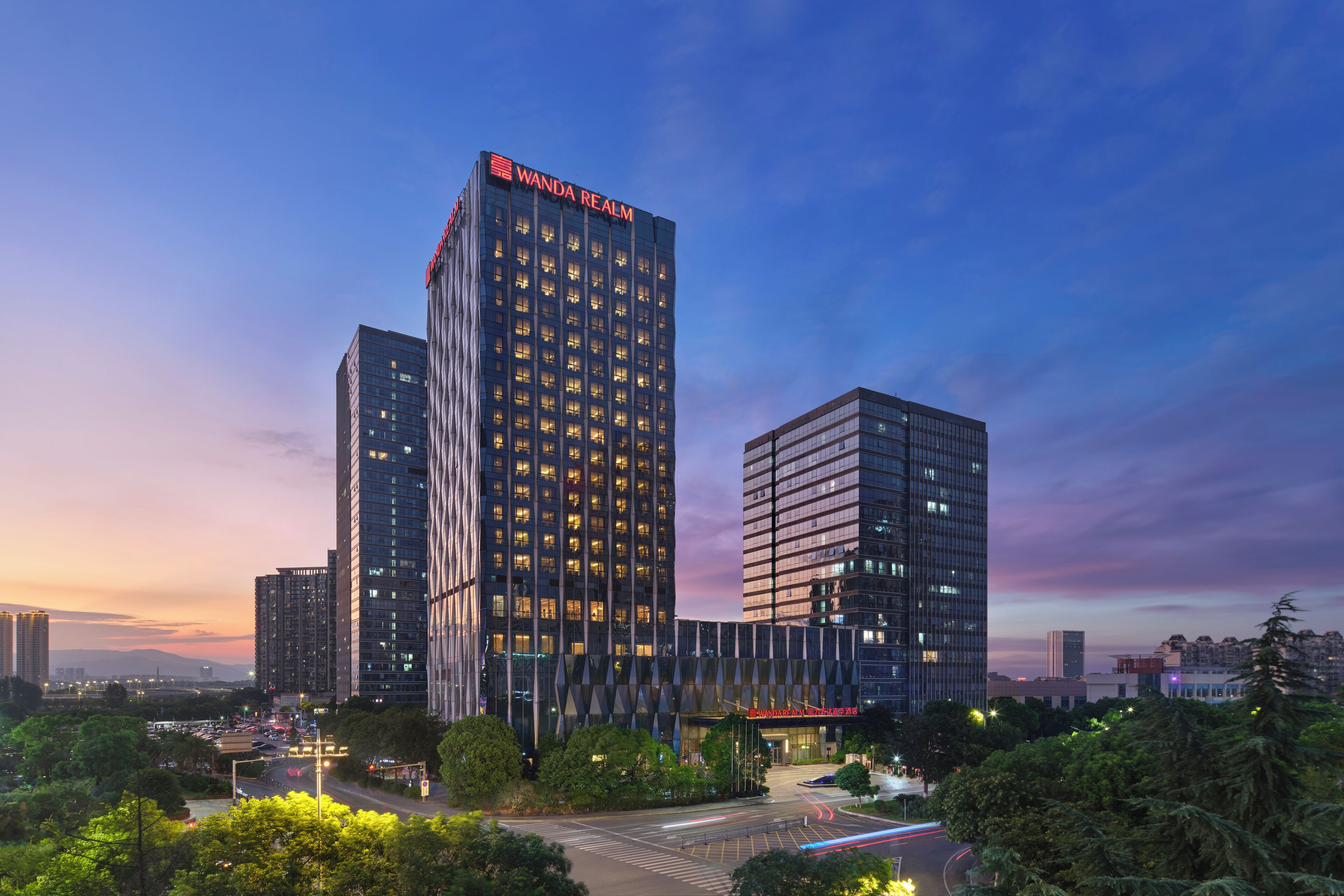 Un immeuble moderne de grande hauteur, sur lequel le nom « Wanda Realm » est affiché en grand sur la façade.