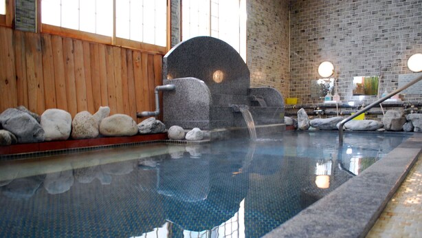 An indoor pool with a stone arch, wooden walls, and a tiled floor. - Hotel Ryusendo Aizan (Iwaizumi)