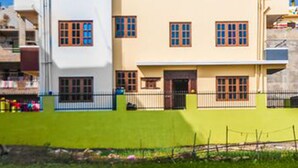 A multi-story building with a flat roof and a staircase leading to an upper level. - Be Here Now Guest House (Kathmandu)