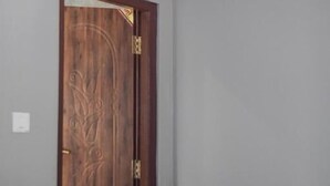 A room with a wooden door, a ceiling with a decorative design, and a plain wall. - Be Here Now Guest House (Kathmandu)