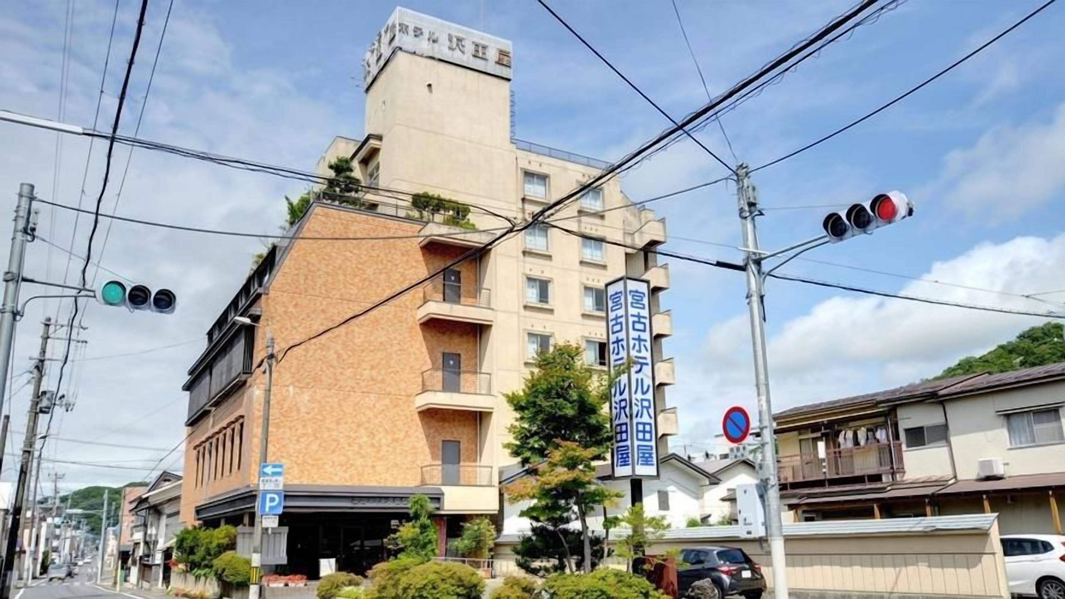 A multi-story building with a parking sign, a no parking sign, and a traffic light.