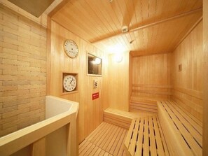 Uma sala de sauna com paredes, bancos e um relógio de madeira.