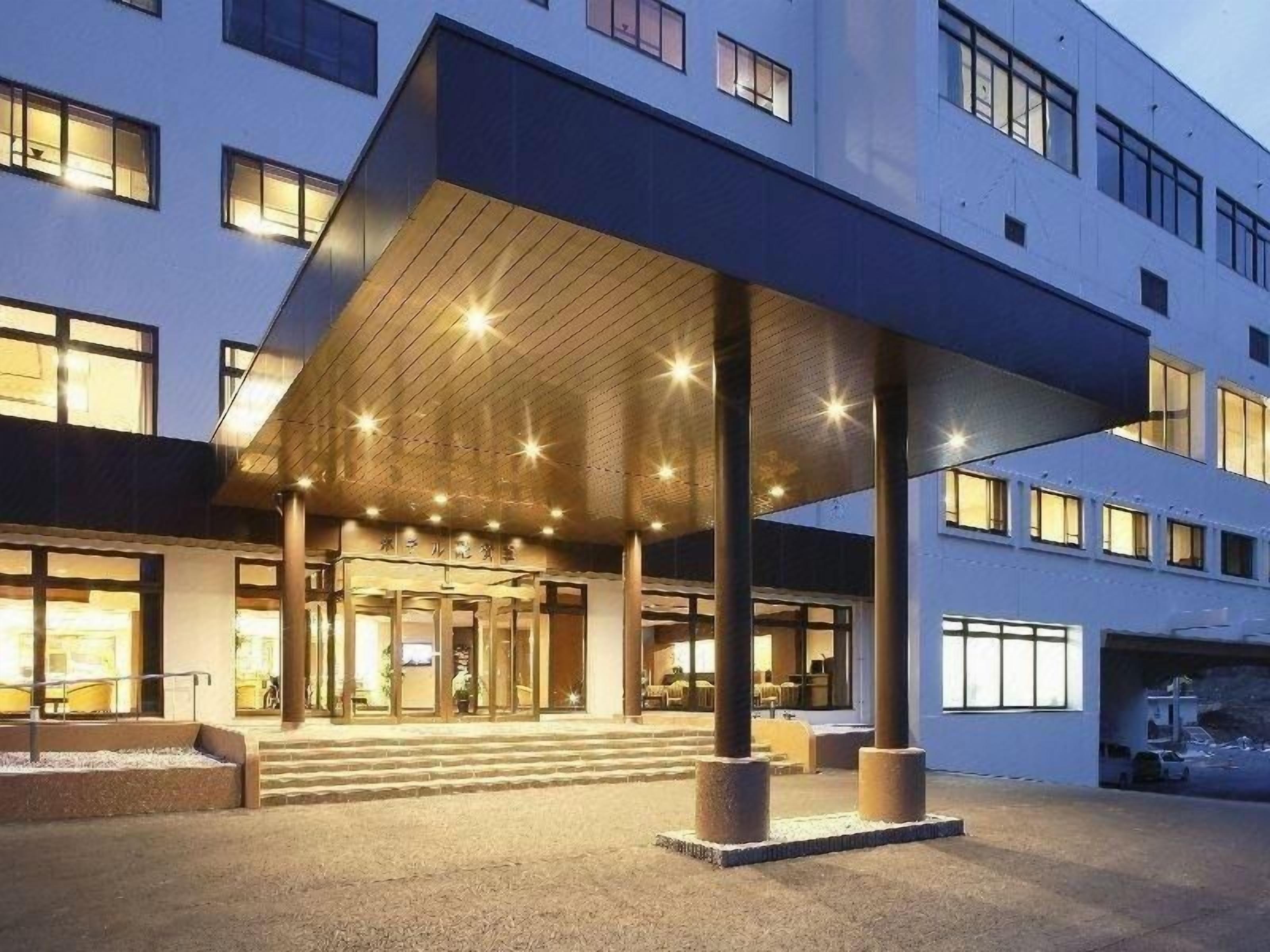 A hotel entrance with a covered walkway, steps leading to the entrance, and a building facade with windows.