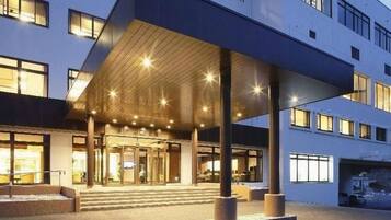A hotel entrance with a covered walkway, steps leading to the entrance, and a building facade with windows.