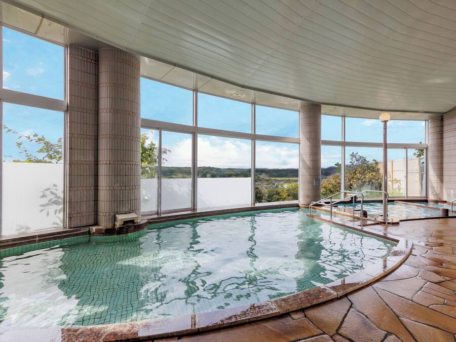 An indoor swimming pool with clear views of the surrounding landscape through large windows.