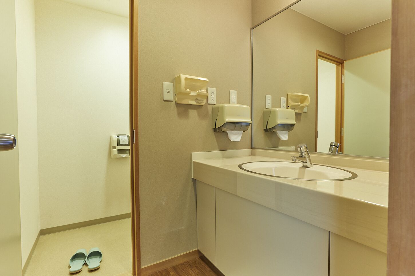 A modern bathroom with a sink, mirror, and hand dryers.