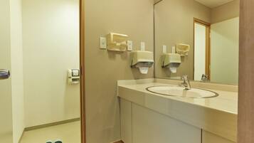 A modern bathroom with a sink, mirror, and hand dryers.