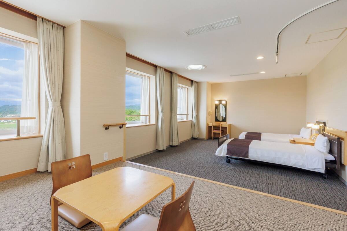 Habitación de hotel con cama, escritorio, silla y vistas al exterior.