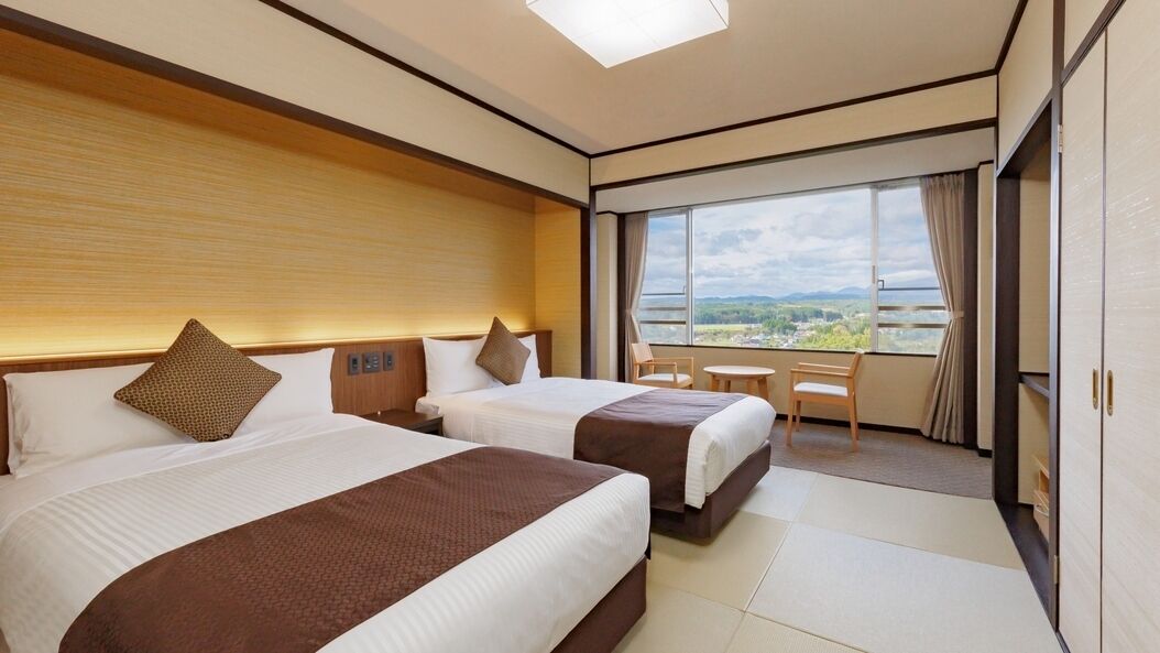 Habitación de hotel con dos camas, un balcón y vistas del paisaje.