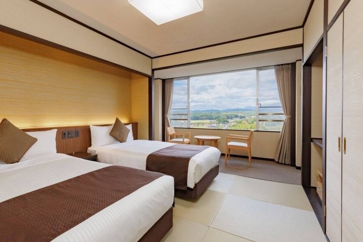 Habitación de hotel con dos camas, un balcón y vistas del paisaje.