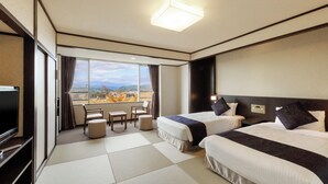 Habitación de hotel con dos camas, televisión, escritorio y vistas a la montaña.