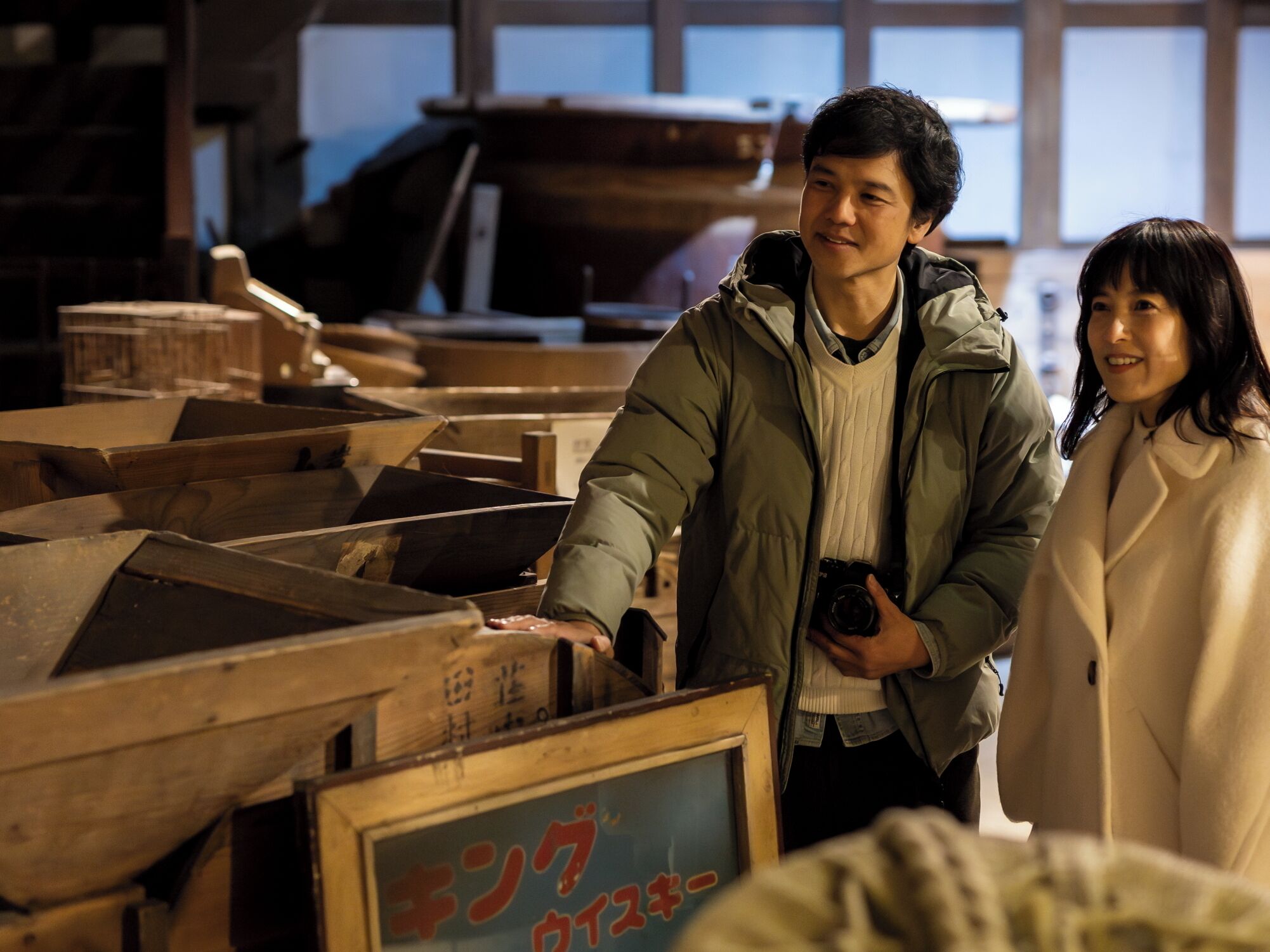 Un hombre y una mujer en un almacén con cajas de madera y un letrero con caracteres japoneses.