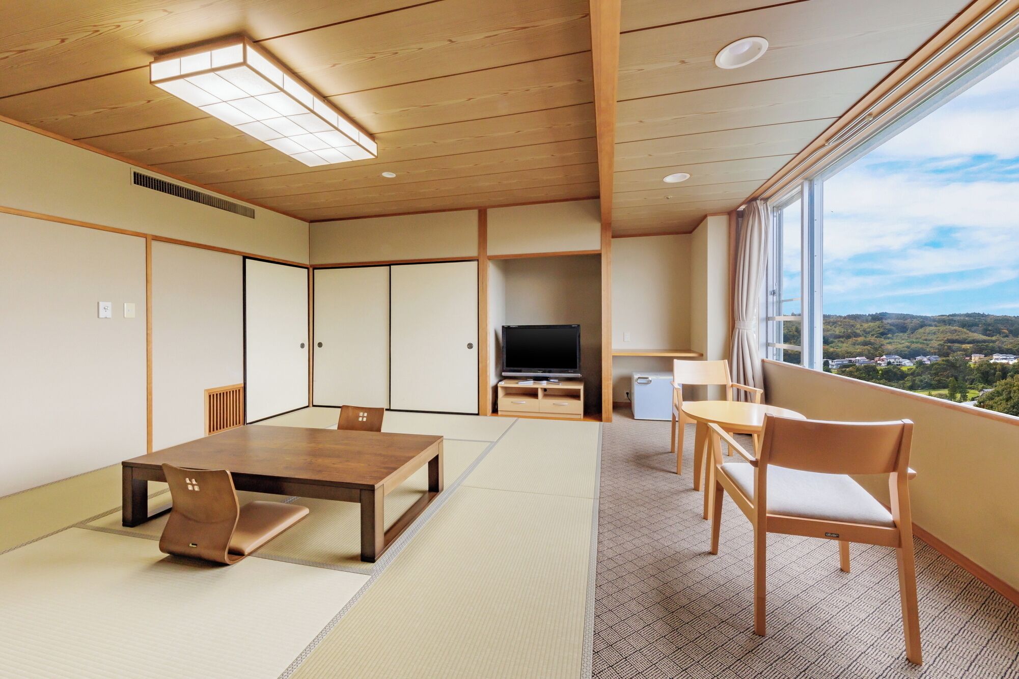 A traditional Japanese-style room with tatami flooring, a low wooden table, and a television.