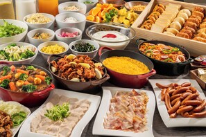Un buffet proposant une variété de plats, notamment des salades, des viandes et du pain.