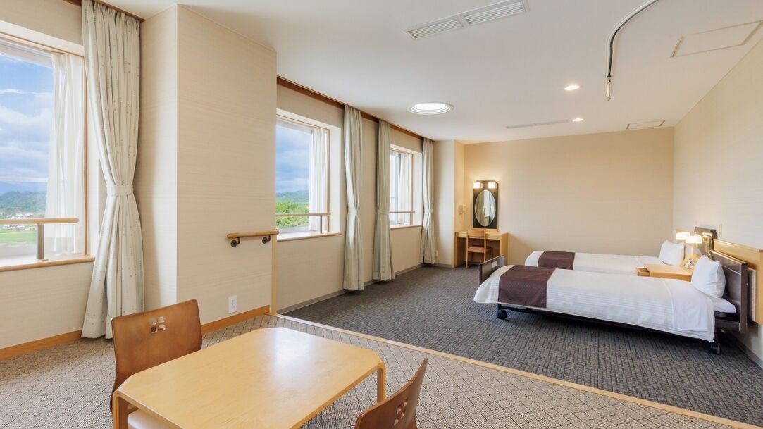 Habitación de hotel con cama, escritorio, silla y vistas al exterior.