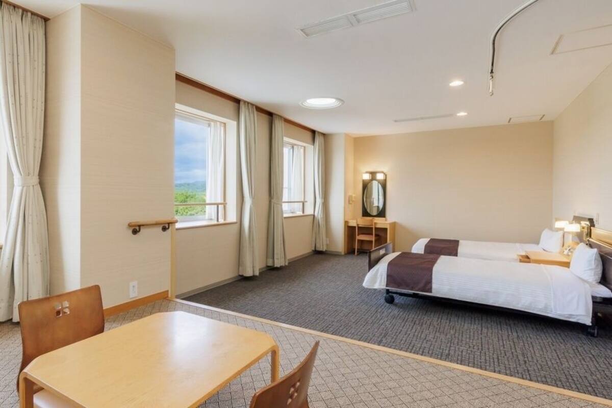 Habitación de hotel con cama, escritorio, silla y vistas al exterior.
