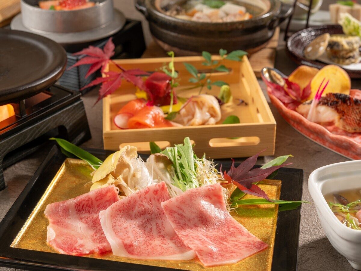 A dining table with various food items, including sliced meat and vegetables, and a hot pot setup.