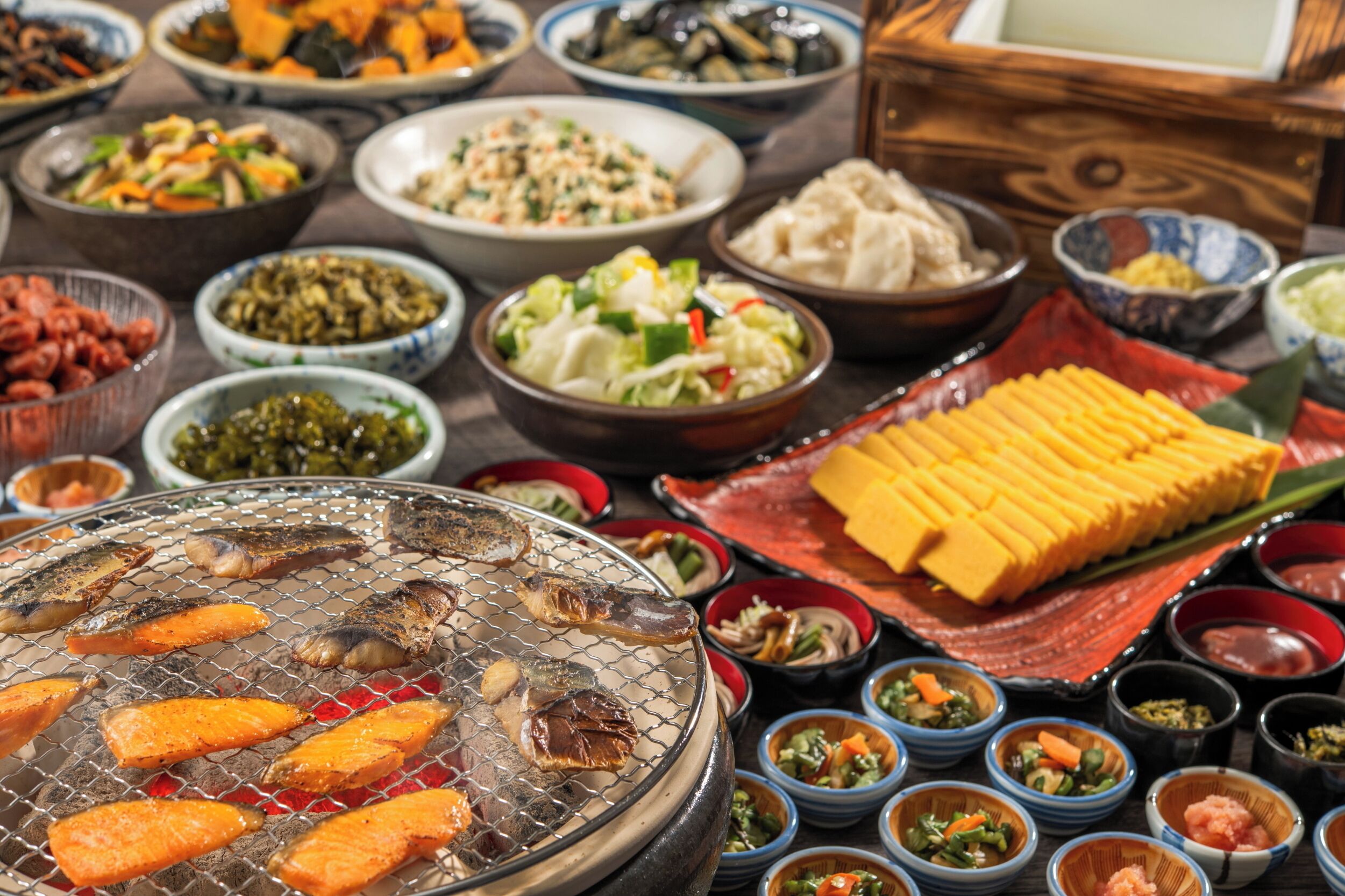 A variety of dishes and a grill with food being cooked.