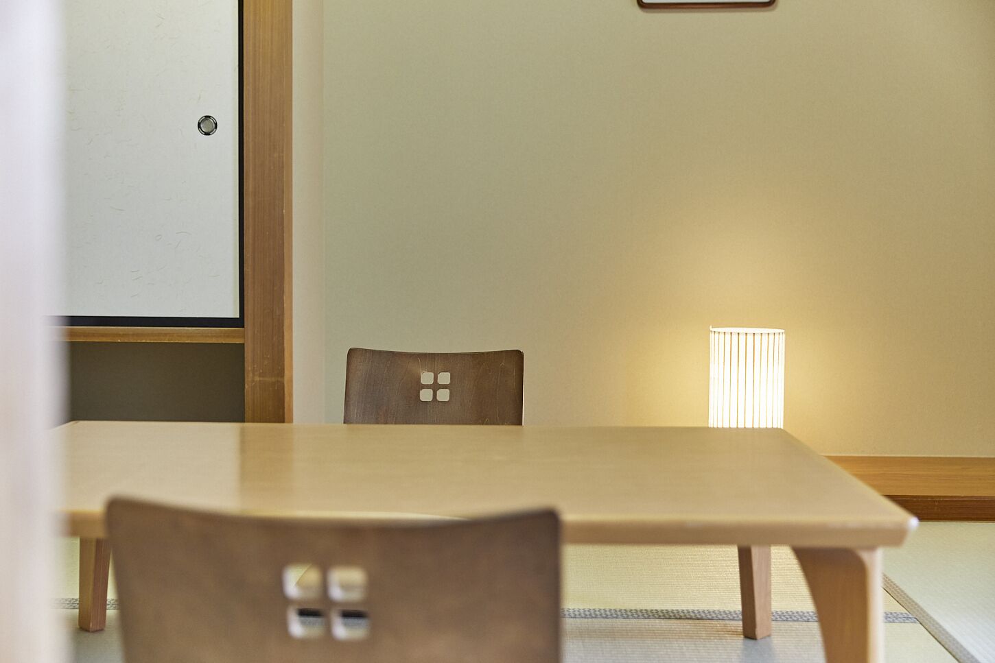 A room with a wooden table and chairs, a whiteboard, and a window with blinds.
