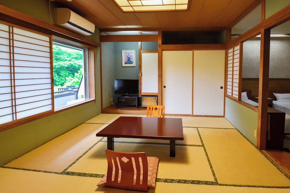 Ein traditioneller japanischer Raum mit Tatami-Bodenbelag, einem niedrigen Tisch und verschiebbaren Türen.