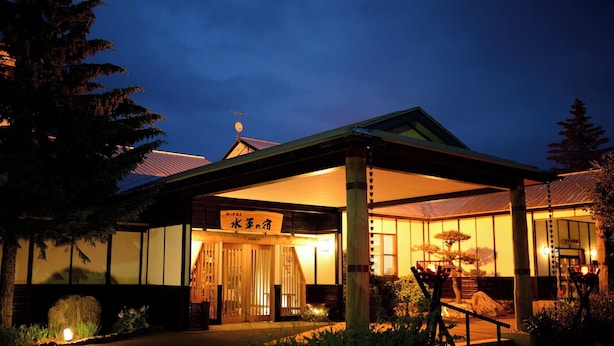 A traditional Japanese building with a covered entrance, wooden pillars, and a sign with Japanese characters. - Suigun no Yado (Ajigasawa)