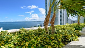 A balcony with a view of the ocean and tall buildings in the background. - Icon Residences (Miami)