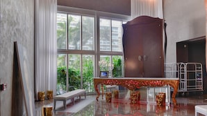 A spacious room with a large window, a wooden cabinet, a bench, and a metal rack. - Icon Residences (Miami)