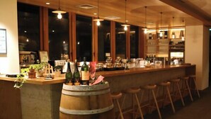 A bar area with wooden stools, a large barrel, and bottles on the counter. - Hotel Folkloro Hanamaki Towa (Hanamaki)