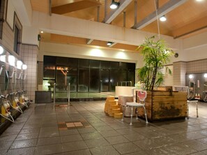Des toilettes publiques équipées de plusieurs sèche-mains, d’un grand miroir et d’une plante en pot.