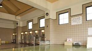 A large indoor swimming pool with tiled walls and ceiling, multiple windows, and a sign on the wall. - Hotel Folkloro Hanamaki Towa (Hanamaki)