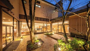 A modern building with a courtyard, glass doors, and outdoor seating areas. - Forest Resort Yamanote Hotel (Daisen)