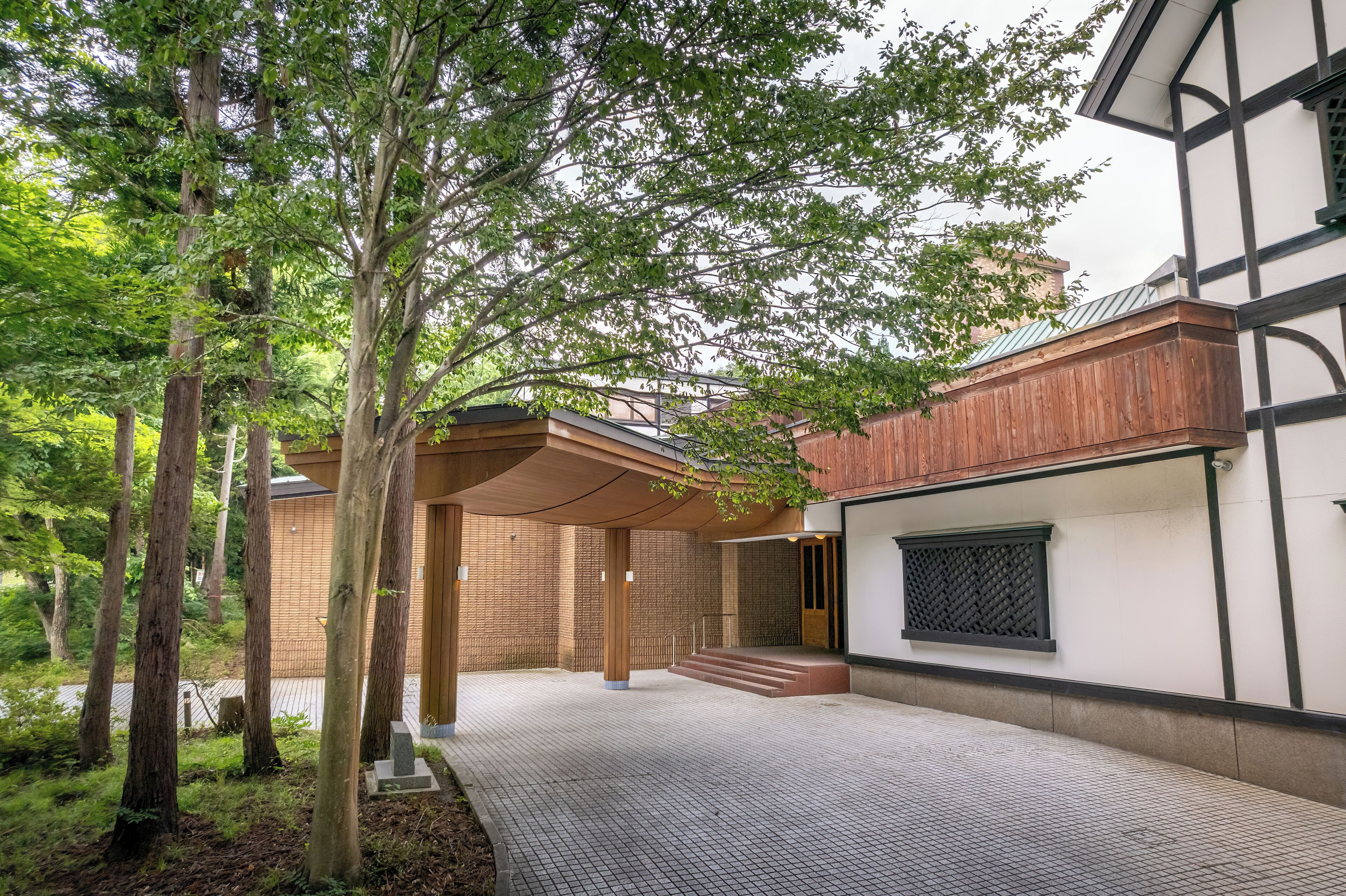 A covered outdoor area with a wooden bench, a brick wall, and a window with a lattice design.