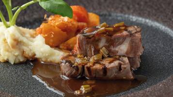 A plate with a piece of meat, mashed potatoes, and roasted vegetables.