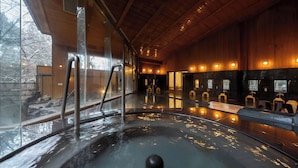 A hot spring bath area with wooden walls and a glass enclosure. - Forest Resort Yamanote Hotel (Daisen)