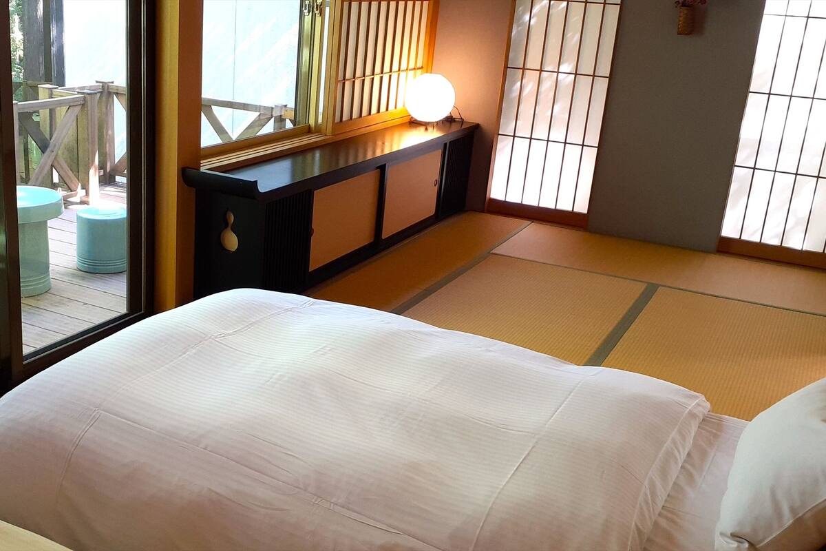 A traditional Japanese-style room with tatami flooring, a low wooden desk, and a sliding shoji screen.