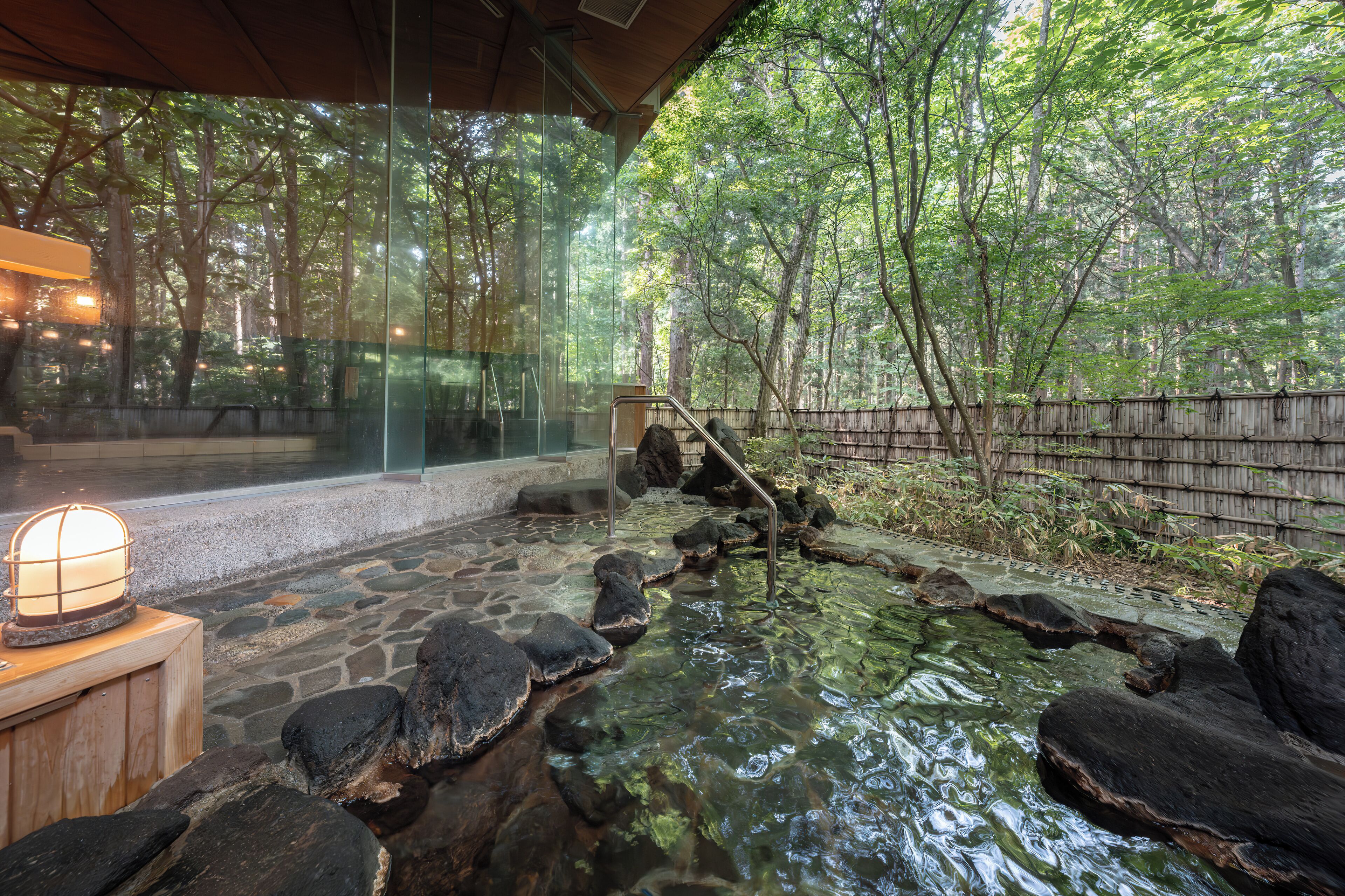 Un jardín interior tranquilo con un sendero de piedra, un pequeño estanque y un banco de madera.