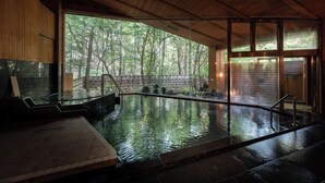 A serene indoor pool area with a view of a forest through large windows. - Forest Resort Yamanote Hotel (Daisen)