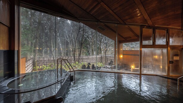A hot tub area with a view of a forested landscape through large windows. - Forest Resort Yamanote Hotel (Daisen)