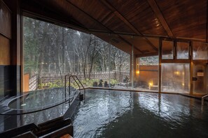 Un espace avec un bain à remous offrant une vue sur un paysage boisé grâce à de grandes fenêtres.