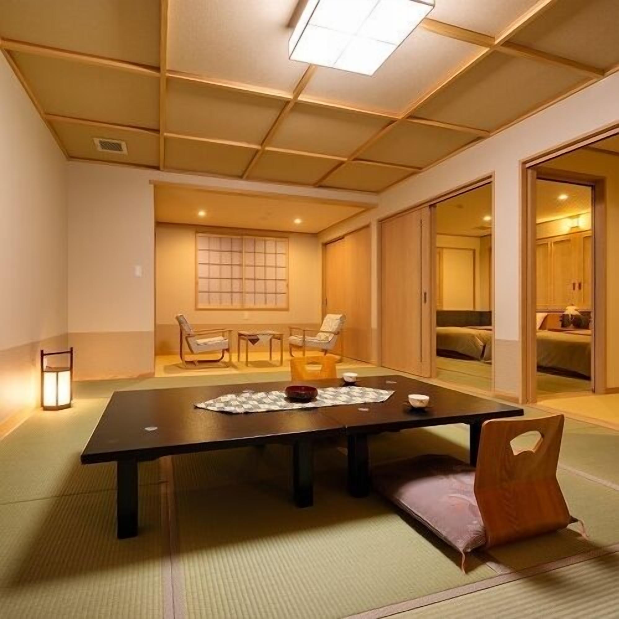 Une pièce de style japonais traditionnel, avec un sol recouvert de tatamis, une petite table avec un set de table, un paravent shoji et des portes coulissantes donnant sur une chambre à coucher.