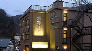 A multi-story building with a prominent sign, a fire escape, and a gated entrance. - Mukaitaki Ryokan (Fukushima)