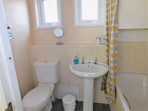 Un baño pequeño con inodoro, lavamanos y ducha.
