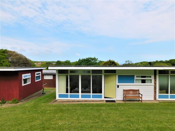 Een gelijkvloers huis met plat dak, een voortuin en een kleine veranda.