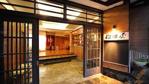 A traditional Japanese interior with tatami flooring, a reception desk, and a sign with Japanese characters. - Matsudaya Ryokan (Hanamaki)