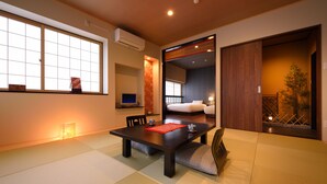 A traditional Japanese room with tatami flooring, a low table with cushions, a sliding door, and a view of a garden. - Matsudaya Ryokan (Hanamaki)