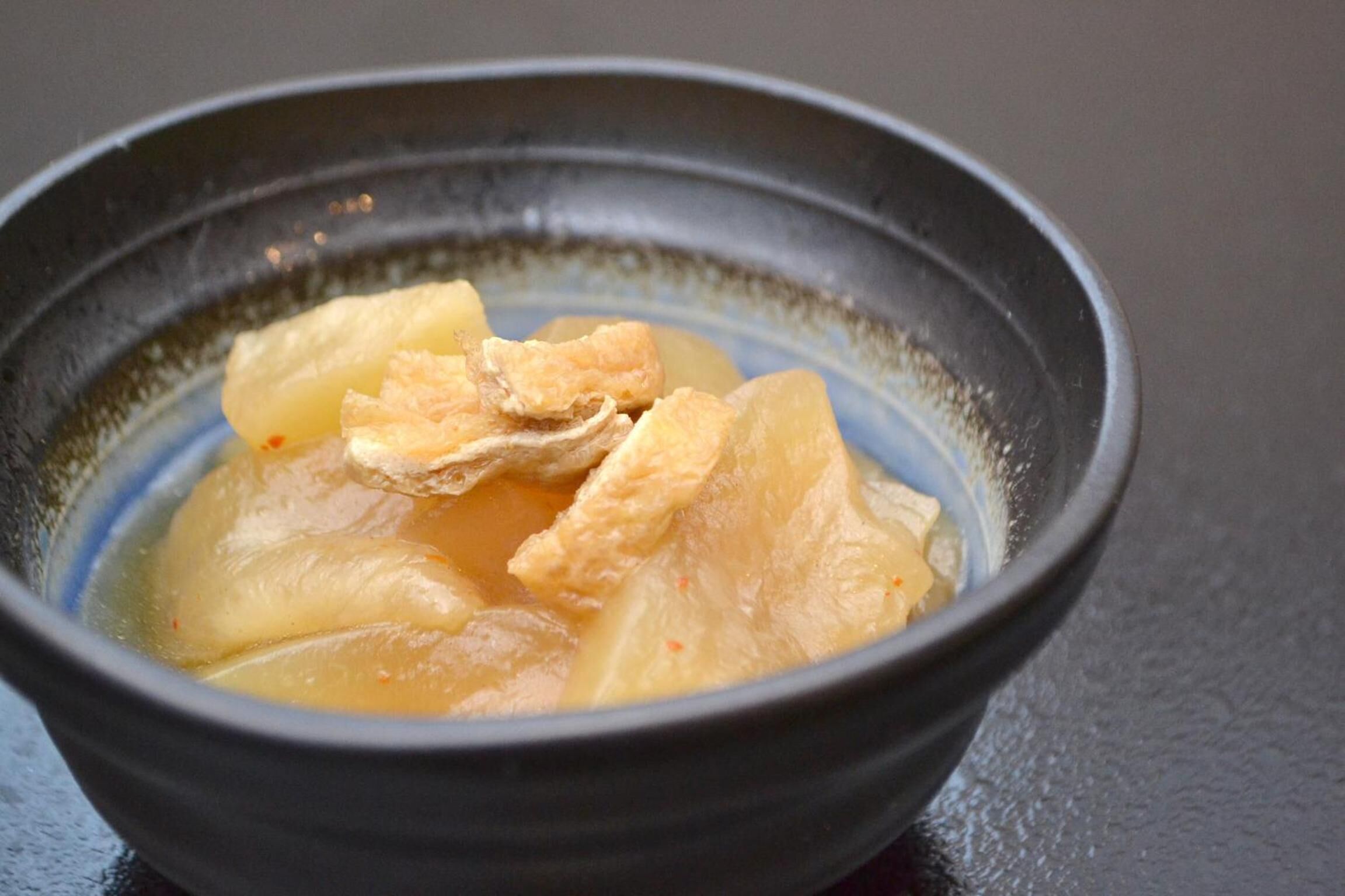A bowl of soup with tofu and vegetables.