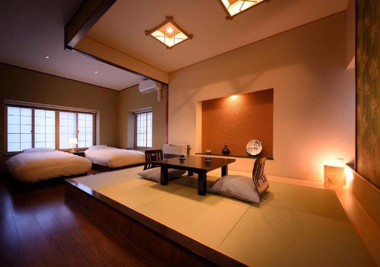 A traditional Japanese-style room with tatami flooring, a low table, cushions, and a shoji screen.
