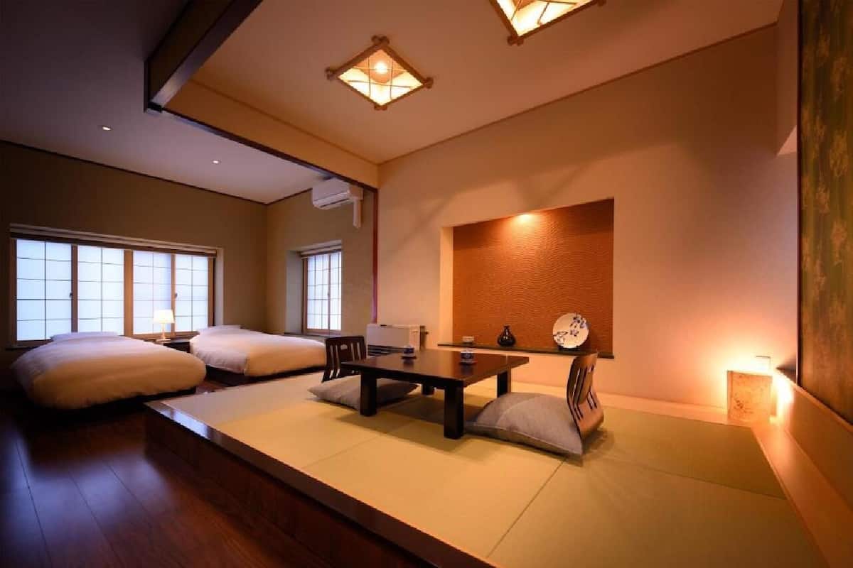 Ett traditionellt japanskt rum med tatamimattor på golvet, ett lågt bord, kuddar och en shoji-skärm.