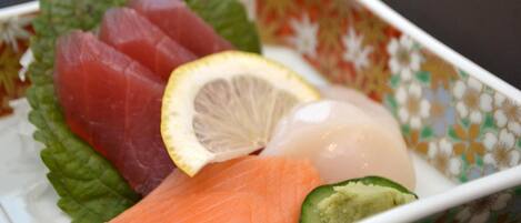 A bowl of sashimi with salmon, tuna, and a lemon slice.
